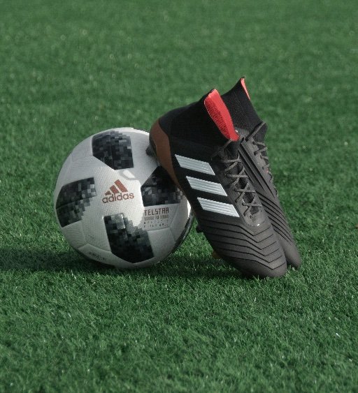 adidas soccer cleat next to ball on artificial turf