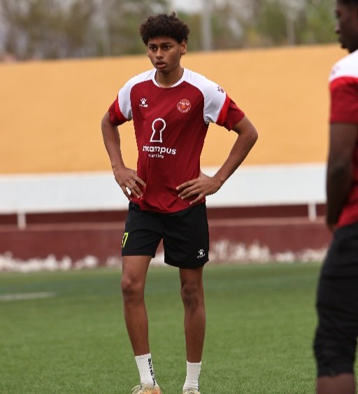 Murcia Football Academy player standing with hands on hips on pitch